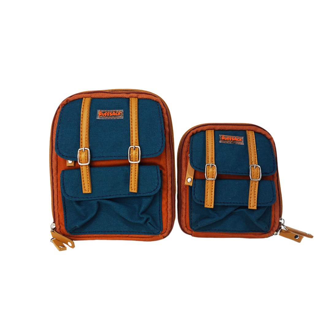 Dale Rust model Ruffsack backpack front angle. The backpack face features a cotton dark green solid pattern with two small front buttoned pockets atop a cotton rust colored solid pattern. Tan faux leather accents are on the front and sides of the bag. A side zipper allows access to the inside.