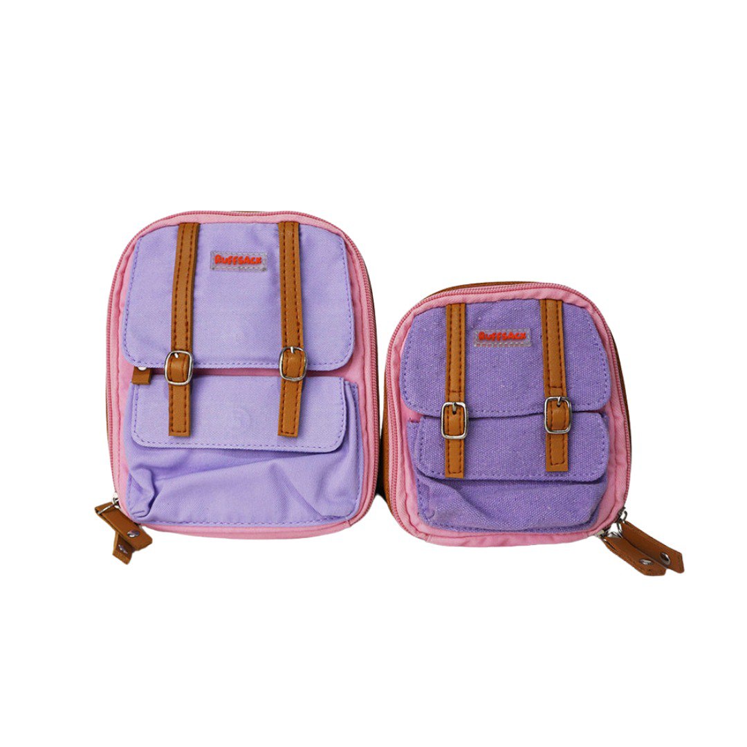 Dale Pink model Ruffsack backpack front angle. The backpack face features a cotton purple solid pattern with two small front buttoned pockets atop a cotton pink solid pattern. Tan faux leather accents are on the front and sides of the bag. A side zipper allows access to the inside.